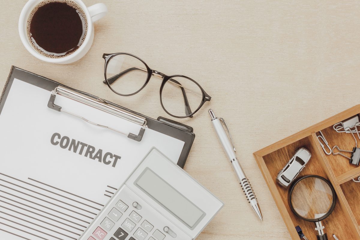 top view business contract form with coffee eyeglasses car calculator pen with magnifying glass wooden background